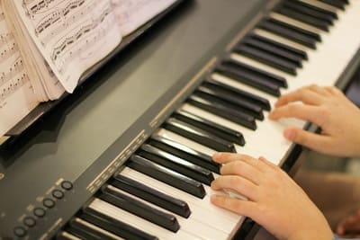 Hände am Klavier mit aufgeschlagenen Noten